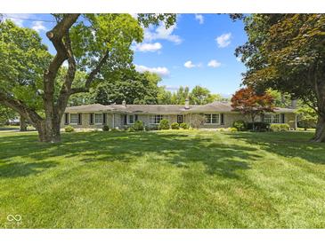 Ranch home with stone accents, mature trees, manicured lawn, and blue skies at 618 Mellowood Dr, Indianapolis, IN 46217