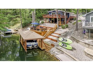 Beautiful lake house featuring a private boat dock, a wooden deck, and a wooded lot at 6497 Osprey Dr, Nineveh, IN 46164