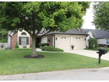 Charming home featuring a large tree, brick accents, and a well-maintained front lawn and two-car attached garage at 7662 Micawber Ct, Indianapolis, IN 46256