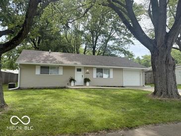 Charming single-story home with lush green lawn, complemented by mature trees at 1306 Woodbine Dr, Anderson, IN 46011