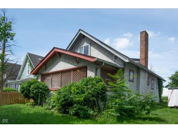 Exterior view of a home featuring a stucco facade, brick chimney, and lattice details at 320 N Colorado Ave, Indianapolis, IN 46201