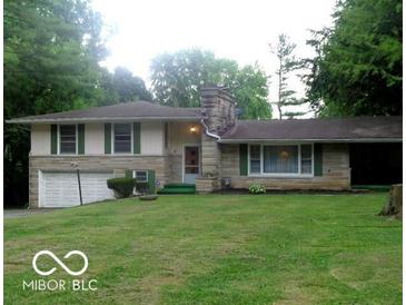 Charming single-story home with stone accents, lush lawn, and attached two-car garage at 3253 W 34Th St, Indianapolis, IN 46222