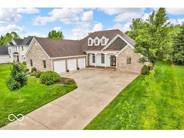 Beautiful brick home featuring an attached three-car garage and a well-manicured lawn with colorful flower beds at 720 Willow Pointe North Dr, Plainfield, IN 46168