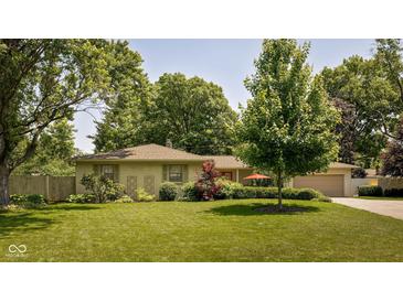 Charming ranch-style home featuring a well-manicured lawn and mature trees in a desirable neighborhood at 7401 N Layman Ave, Indianapolis, IN 46250