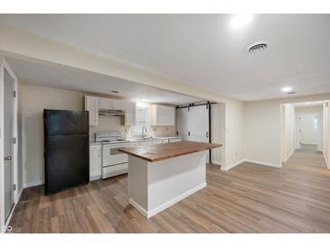 Open kitchen features white cabinetry, an island with wood countertop, and stainless steel appliances at 2009 N New York Ave, Muncie, IN 47304