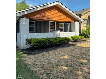 Charming front porch with freshly painted white brick and dark siding and a wood plank ceiling at 2543 Union St, Indianapolis, IN 46225