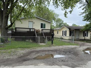 View of a two yellow houses with a fenced yard and an old driveway at 3301 S Lockburn St, Indianapolis, IN 46221