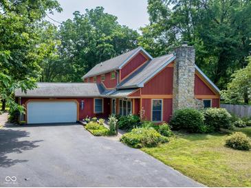 Charming two-story home with a stone chimney, attached garage, and professionally landscaped yard at 5631 Shelby St, Indianapolis, IN 46227