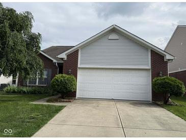 Charming brick home featuring an attached two-car garage and well-maintained landscaping at 621 Appleseed Way, Indianapolis, IN 46217