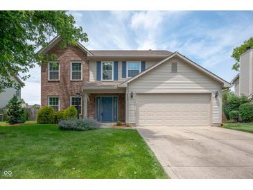 Charming two-story home featuring a well-manicured lawn, blue door, and a mix of brick and siding at 6562 Quail Run, Fishers, IN 46038
