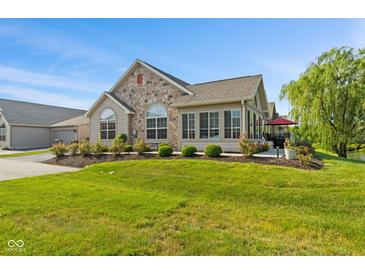 Inviting home featuring a stone front, arched windows, green lawn and outdoor patio at 7850 King Post Dr, Indianapolis, IN 46237