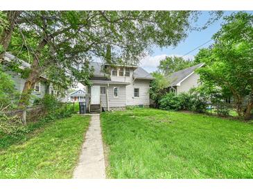 Cozy home boasts a spacious backyard with a long concrete walkway and lush greenery at 806 N Gray St, Indianapolis, IN 46201