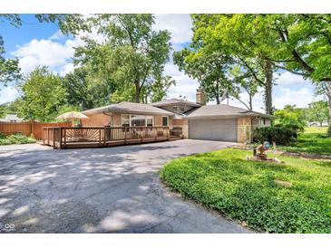 Back exterior of home featuring large deck, well-maintained lawn and mature trees at 1340 Eustis Dr, Indianapolis, IN 46229