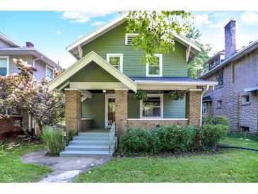 Charming two-story home featuring a cozy front porch with brick accents and lush landscaping at 39 N Bosart N Ave, Indianapolis, IN 46201
