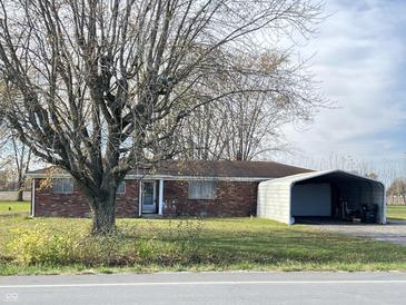 Charming single-story brick home featuring mature trees, a covered entry, and a detached carport at 9842 N State Road 9, Pendleton, IN 46064