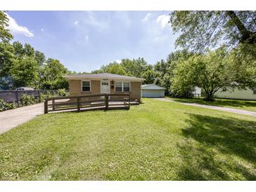 Cozy single-story home with a brick facade, a ramp, a well-maintained lawn and a detached garage at 1217 S Ewing St, Indianapolis, IN 46203