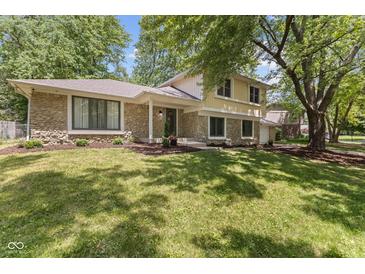 Elegant home featuring stone detailing, lush green lawn, and mature trees adding curb appeal at 1930 Bechtel Rd, Indianapolis, IN 46260