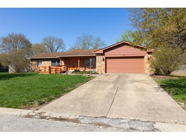 Charming single-story home with an attached garage, well-kept lawn, and a inviting orange front door at 40 S Restin Rd, Greenwood, IN 46142