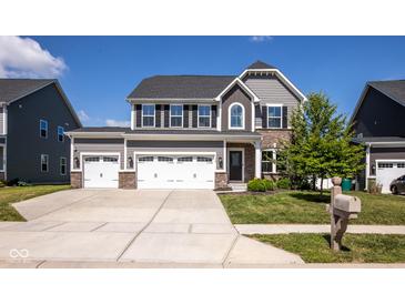 Charming two-story home with a three-car garage, manicured lawn, and beautiful architectural details at 7128 Verwood Ct, Plainfield, IN 46168