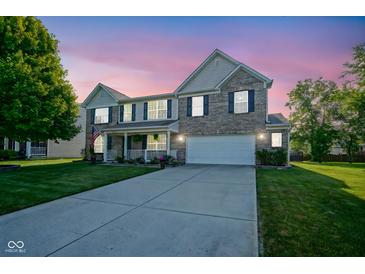 Charming two-story home with well-manicured lawn and inviting front porch at dusk at 12847 Arvada Pl, Fishers, IN 46038