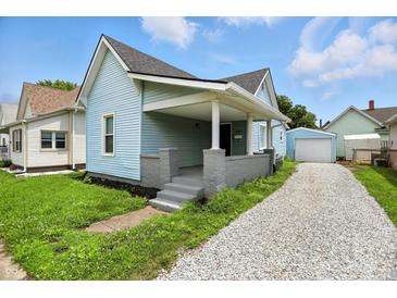 Charming home with a covered front porch, light blue siding and gravel driveway at 410 Montgomery St, Shelbyville, IN 46176