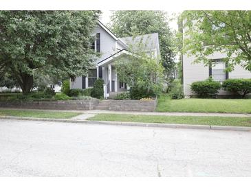 Charming home featuring mature trees, a well-manicured lawn, and a welcoming front porch at 633 N East St, Greenfield, IN 46140