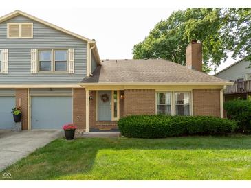 Charming home featuring mixed siding, brick, an attached two car garage and a neatly manicured lawn at 7612 Farm View E Cir, Indianapolis, IN 46256