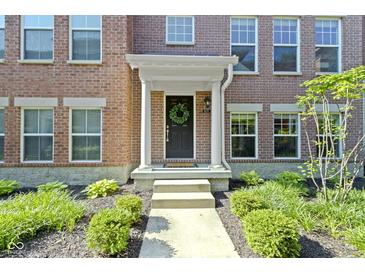 Charming brick home featuring a welcoming front door with decorative wreath and covered porch at 9476 Oakley Dr, Indianapolis, IN 46260