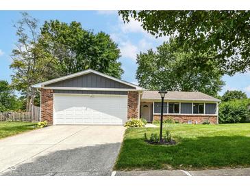 Charming brick home with a two-car garage, green lawn, and mature trees at 12020 Colbarn Dr, Fishers, IN 46038