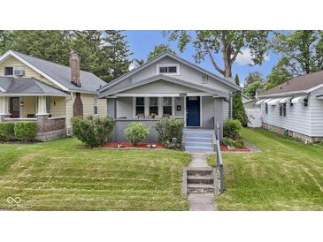 Charming bungalow with a well-maintained front yard, shrubbery, and inviting blue front door at 5209 E North St, Indianapolis, IN 46219