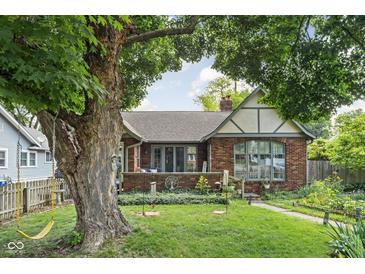 Charming brick home featuring a well-maintained front yard with mature trees and landscaping at 4901 N Kenwood Ave, Indianapolis, IN 46208