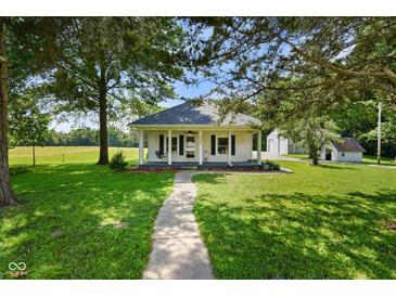 Charming home featuring a covered porch, beautiful landscaping, and mature trees on a well-maintained lawn at 6208 S 200 W, Trafalgar, IN 46181