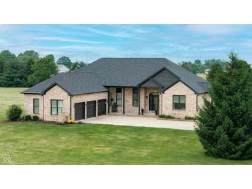 Attractive brick home with a three car garage, lush greenery, and a well-maintained lawn, exemplifying suburban charm at 7702 N County Road 300 W, Lizton, IN 46149