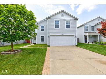 Charming two-story home featuring light gray siding, a spacious two-car garage, and a well-manicured front yard with lush green grass at 9593 W Constellation Dr, Pendleton, IN 46064