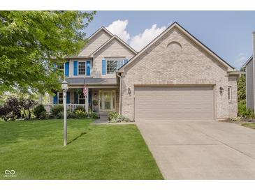 Charming two-story home featuring blue shutters, a covered front porch, and a well-manicured lawn at 13214 Dunwoody Ln, Carmel, IN 46033