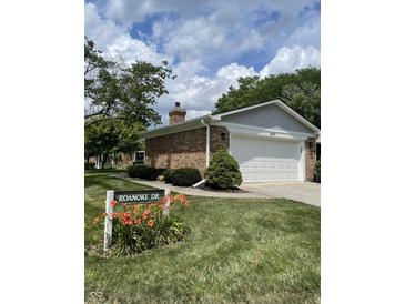 Charming home featuring a well-maintained lawn, flower beds, and a brick exterior with a two-car garage at 1540 Roanoke Dr, Zionsville, IN 46077