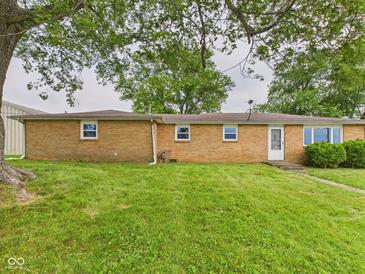 A brick home exterior is showcased with a green lawn and trees, offering a serene backyard view at 203 Plum E St, Frankton, IN 46044