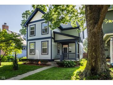 Charming two-story home features blue and grey siding, covered porch, well-kept landscaping, and mature trees at 2347 N Pennsylvania St, Indianapolis, IN 46205