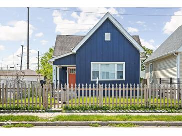 Charming blue home featuring a well-manicured lawn, a picket fence and a bright orange front door at 413 E Caven St, Indianapolis, IN 46225