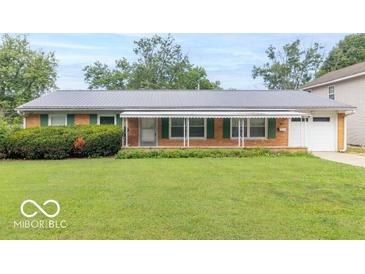 Charming single-story brick home with a well-manicured lawn, covered porch, and attached garage at 814 N Noble St, Greenfield, IN 46140