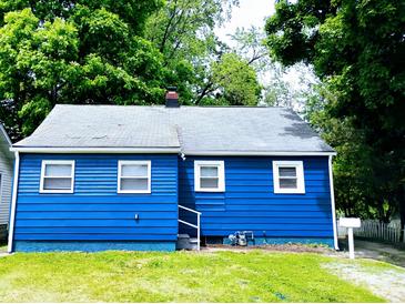 Charming blue home with a well-maintained lawn and mature trees surrounding the property at 94 N Routiers Ave, Indianapolis, IN 46219
