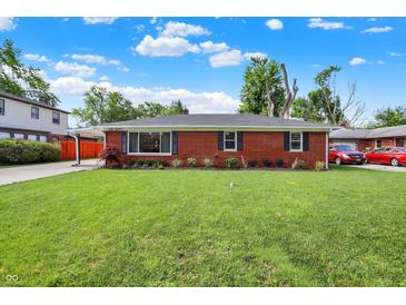 Charming brick home with a well-maintained lawn and mature trees on a sunny day at 5015 Nowland Ave, Indianapolis, IN 46201