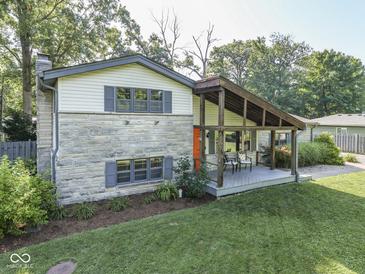 Two story home featuring a covered porch, stone accents, and lush landscaping at 6019 S Tacoma Ave, Indianapolis, IN 46227