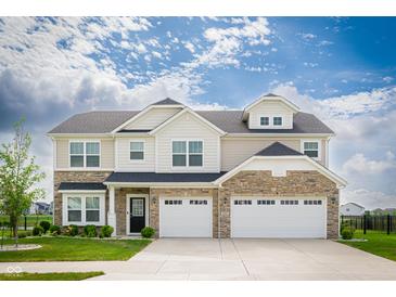 Beautiful two-story home with a stone facade and attached three-car garage, complete with manicured lawn at 7147 Prelude Rd, Brownsburg, IN 46112