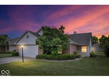 Charming home with a well-maintained lawn, mature tree, and a two-car garage under a colorful, vibrant sky at 8213 Thoroughbred Run, Indianapolis, IN 46256
