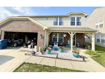 Two-story home featuring a covered front porch, brick accents, and an attached garage filled with recreation equipment at 9628 Gull Lake Dr, Indianapolis, IN 46239
