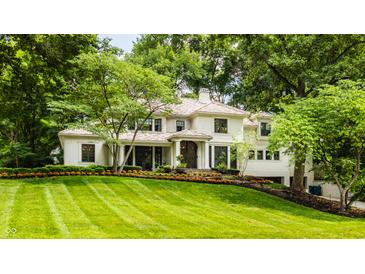 Elegant home with manicured lawn, lush landscaping, and a charming front entrance framed by mature trees at 110 Bow Ln, Indianapolis, IN 46220
