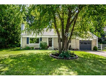 Charming single story home featuring a manicured lawn, gray garage, and a tree in the front yard at 6491 N Oxford St, Indianapolis, IN 46220