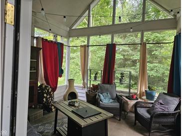Relaxing sunroom with rustic wood pile, chimney and an array of colorful decor and natural lighting at 8423 Mud Creek Rd, Indianapolis, IN 46256