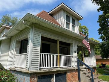 Charming two-story home with American flag, white siding, and covered front porch at 118 S Swain St, Ingalls, IN 46048